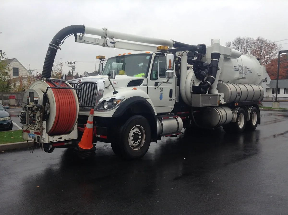 Camion hydrocureur d'assainissement stationné, cuve et enrouleur de flexible visibles