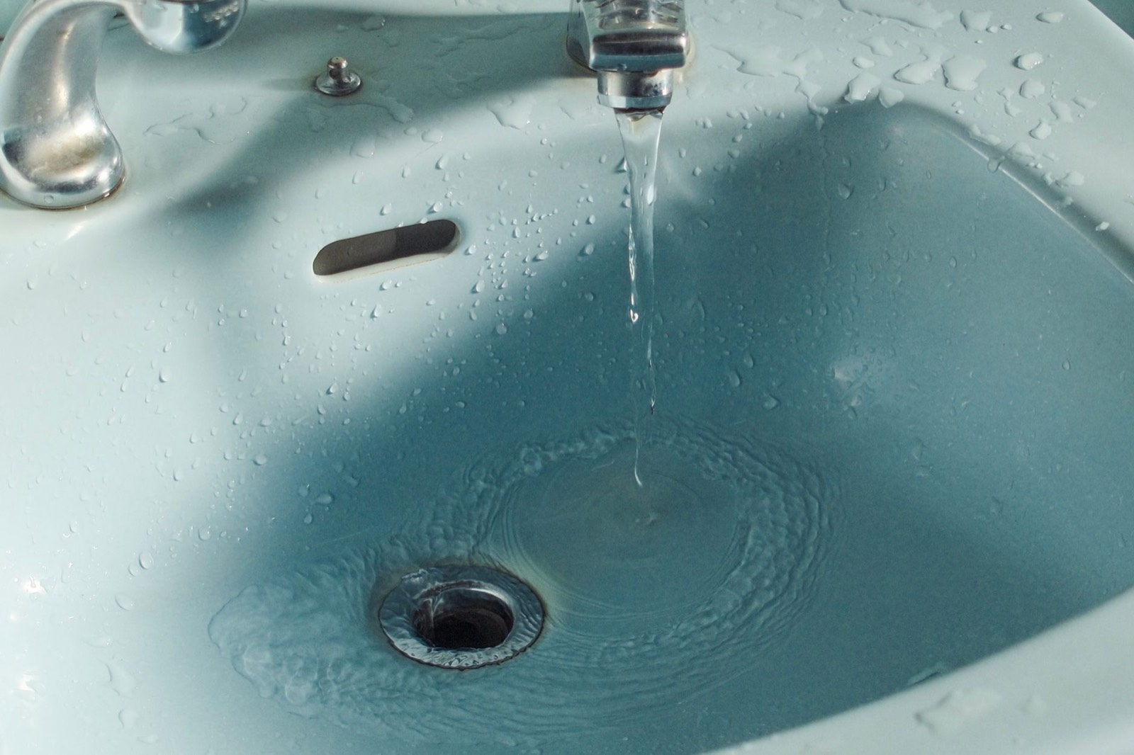 Lavabo ancien et sa bonde d'évacuation dans une salle de bains à rénover
