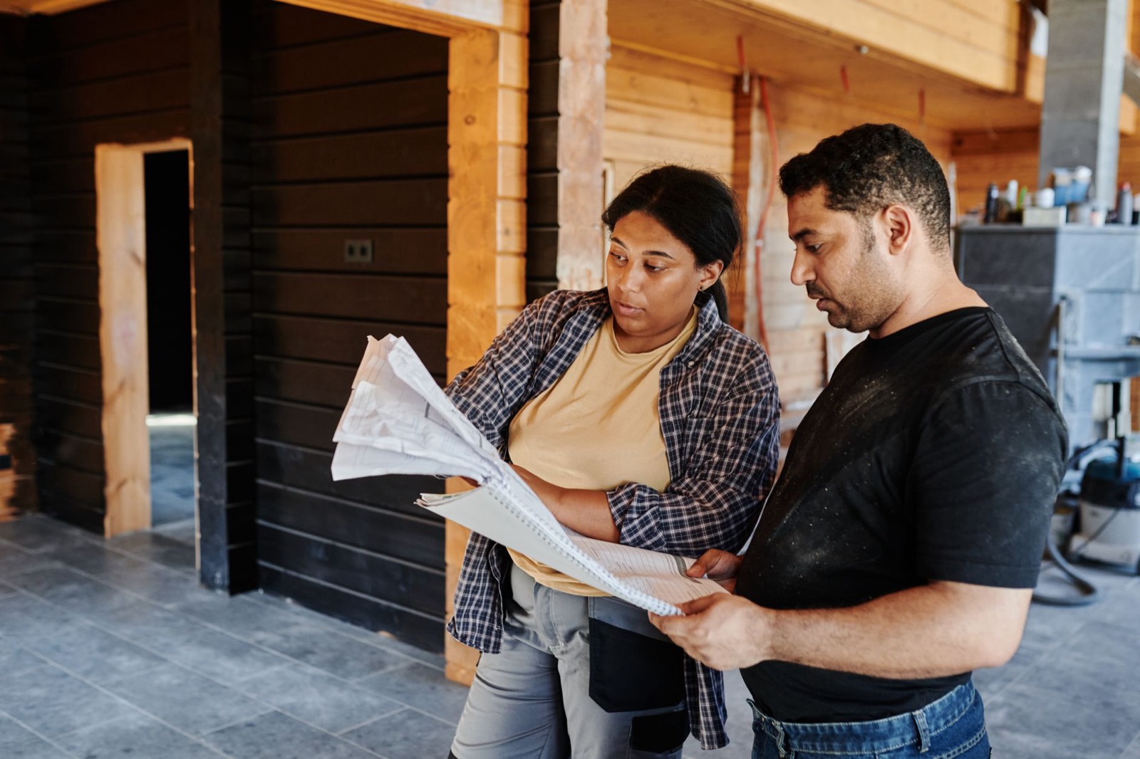 Un artisan et une propriétaire relisent ensemble les plans d'un projet de rénovation